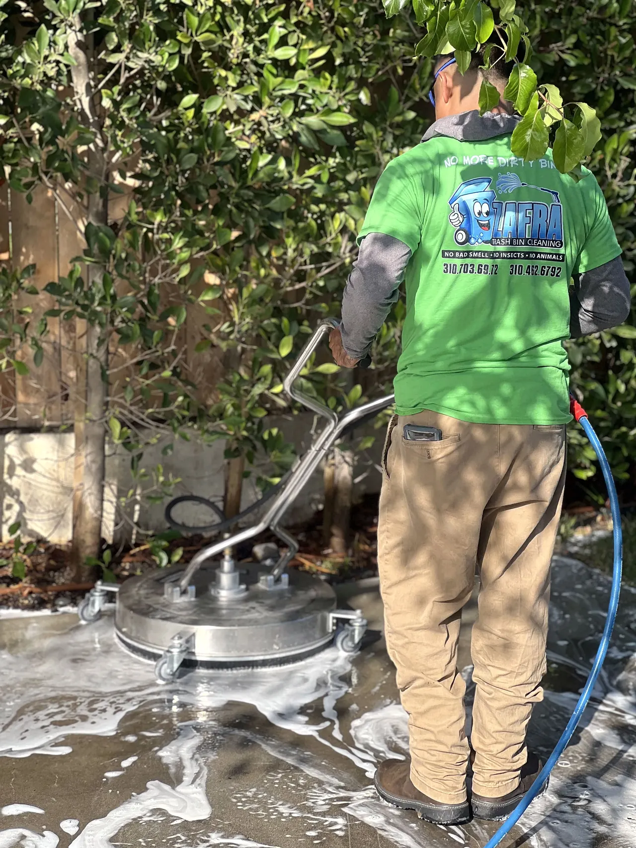 Zafra crew member cleaning a patio with a surface cleaner